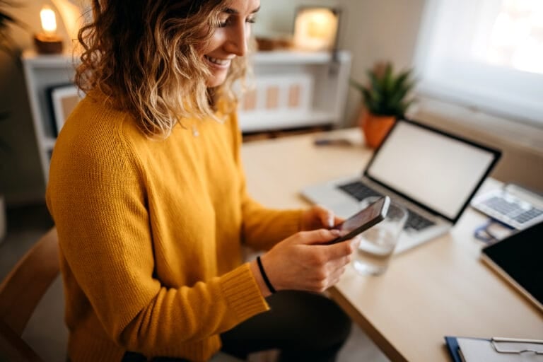 Young woman in a home office using a smart phone.