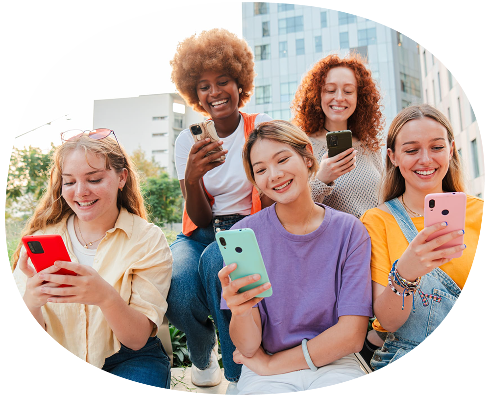 young women sitting outside holding cellphones